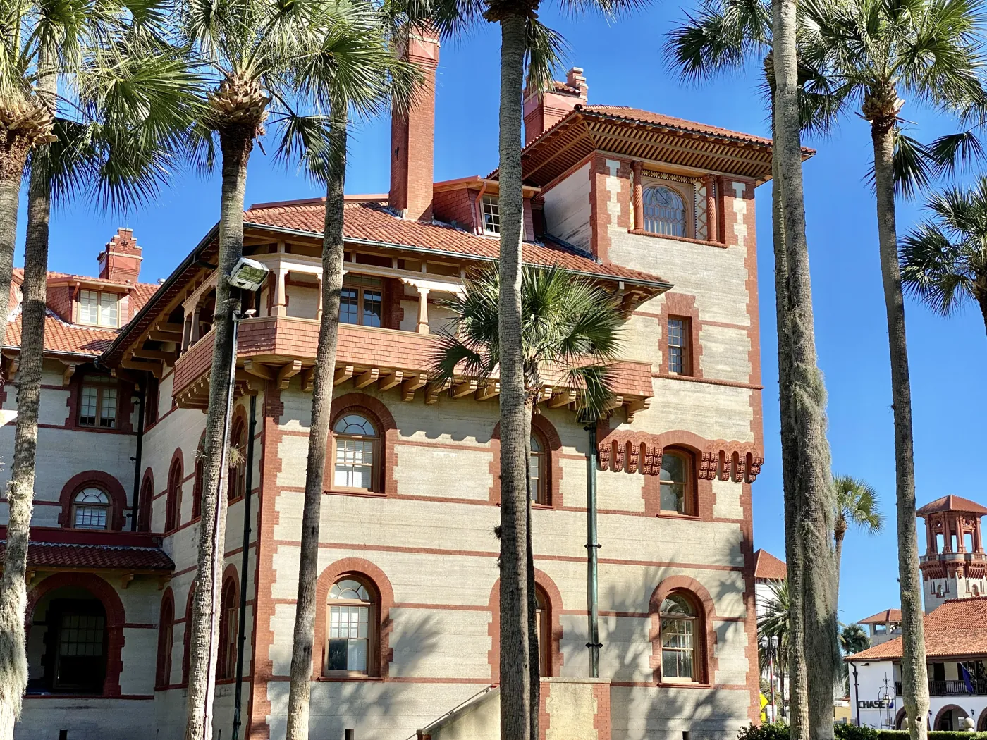 The towers and red tile roofs of Flagler College framed by palm trees.